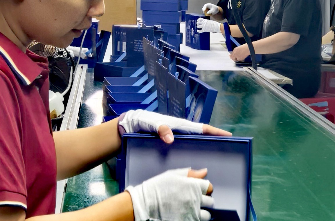 Quality control worker inspecting rigid boxes during production at WEIXIN GROUP